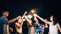 Group of young Asian college student friends lit light sparkler, sing and dance together at beach camping tent Royalty Free Stock Photo