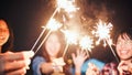 Group of young Asian college student friends lit light sparkler, sing and dance together at beach camping tent Royalty Free Stock Photo