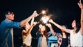 Group of young Asian college student friends lit light sparkler, sing and dance together at beach camping tent Royalty Free Stock Photo