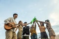 Group of young Asian friends party on vacation enjoy cheering with beer bottle. drinking at camping lake side. hands holding Royalty Free Stock Photo