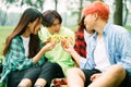 A group of young asians happily eating sandwiches at the park