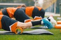 Group of Young Athletes on Stretching Outdoor Session with Foam Rollers and Mats