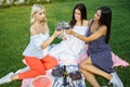 Group of young and beautiful women drink wine in the park.