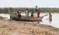 A group of young black African teenage boys from a poor province drag a boat to the shore to prepare for fishing