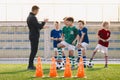 Group of young boys on football training. Kids practicing soccer on grass field. Young man as a soccer coach explain to players tr Royalty Free Stock Photo