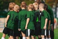 Group of Young Boys in Green Jersey Shirts Standing with Coach on Soccer Field