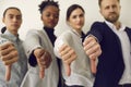 Group of young business people giving thumbs down to show their dislike of bad work