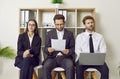 Group of young business people sitting on chairs in a row with resumes and laptop.