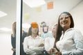 Group of young business people use multi-colored sticker papers posting them on the glass wall working on ideas and