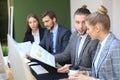 Group of young business people working, communicating while sitting at the office desk together with colleagues