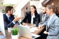 Group of young business people working, communicating while sitting at the office desk together with colleagues. Royalty Free Stock Photo