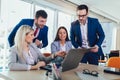 Group of young business people working and using laptop while sitting at the office desk together. Royalty Free Stock Photo