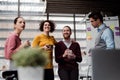 A group of young businesspeople with cup of coffee standing in office, talking. Royalty Free Stock Photo