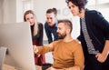 Group of young businesspeople looking at laptop screen in office, discussing issues. Royalty Free Stock Photo