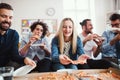 Group of young businesspeople with pizza having lunch in a modern office. Royalty Free Stock Photo