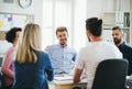 Group of young businesspeople sitting around table in a modern office, having meeting. Royalty Free Stock Photo