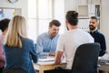 Group of young businesspeople sitting around table in a modern office, having meeting. Royalty Free Stock Photo