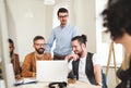 Group of young businesspeople sitting around table in a modern office, having meeting. Royalty Free Stock Photo