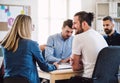 Group of young businesspeople sitting around table in a modern office, having meeting. Royalty Free Stock Photo