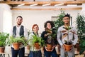 Group of young businesspeople standing in office, holding plants. Royalty Free Stock Photo