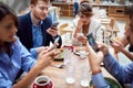 Group of young caucasian people having unsocial lunch in restaurant, using their cell phones and not talking to each other.