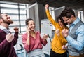 A group of young businesspeople with smartphone standing in office, expressing excitement. Royalty Free Stock Photo