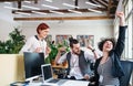 Group of young cheerful businesspeople using laptop in office, expressing excitement. Royalty Free Stock Photo