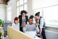 Group of young cheerful businesspeople using laptop in office, start-up concept. Royalty Free Stock Photo