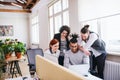 Group of young cheerful businesspeople using laptop in office, start-up concept. Royalty Free Stock Photo