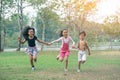 Group of young children happily holding hands and running towards camera in park