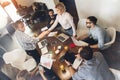 Group of young coworking people meet and make a deal. Man and woman make handshake among business partners. Creative managers sit Royalty Free Stock Photo