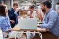 Group of creative people at the table, working on laptop and discussing at cafe