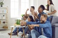 Happy excited multiracial friends cheering while watching football on television Royalty Free Stock Photo