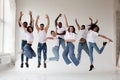 Group of young diverse People dancers jumping on white background in studio. Guys and girls in white t-shirts and jeans Royalty Free Stock Photo