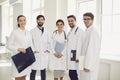 Group of young doctors standing together at hospital hall. Team of medical specialists smiling at camera in clinic Royalty Free Stock Photo