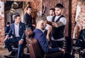 Group of young elegant positive mens pose in interior of barbershop.