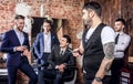 Group of young elegant positive mens pose in interior of barbershop.