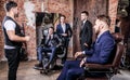 Group of young elegant positive mens pose in interior of barbershop.