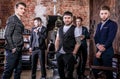 Group of young elegant positive mens pose in interior of barbershop.