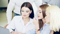 A group of young employees confer in front of a laptop. Focus on the young Beautiful business lady who is involved in