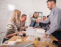 A group of young entrepreneurs discussing their next project at a meeting pointing at the blueprint which is at the middle of the