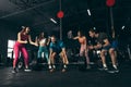 Group of young friends doing sports, training at gym indoors. Strong muscular man lifting heavy barbell Royalty Free Stock Photo