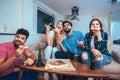 Group of young friends eating pizza and watching tv.Home party. Royalty Free Stock Photo