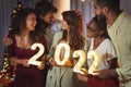 Friends holding illuminative numbers 2022 at New Years Eve midnight countdown Royalty Free Stock Photo