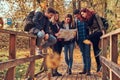 Group of young friends hiking in autumn colorful forest, looking at map and planning hike. Royalty Free Stock Photo