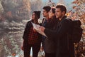 Group of young friends hiking in autumn colorful forest, looking at map and planning hike. Royalty Free Stock Photo