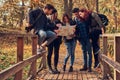 Group of young friends hiking in autumn colorful forest, looking at map and planning hike. Royalty Free Stock Photo