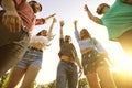 Group of young friends raising their hands in unity, low angle view. Happy people celebrating victory outdoors Royalty Free Stock Photo