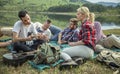 Group of young friends relaxing sitting on the grass near the lake Royalty Free Stock Photo