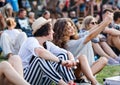 Group of young friends sitting on ground at summer festival. Royalty Free Stock Photo